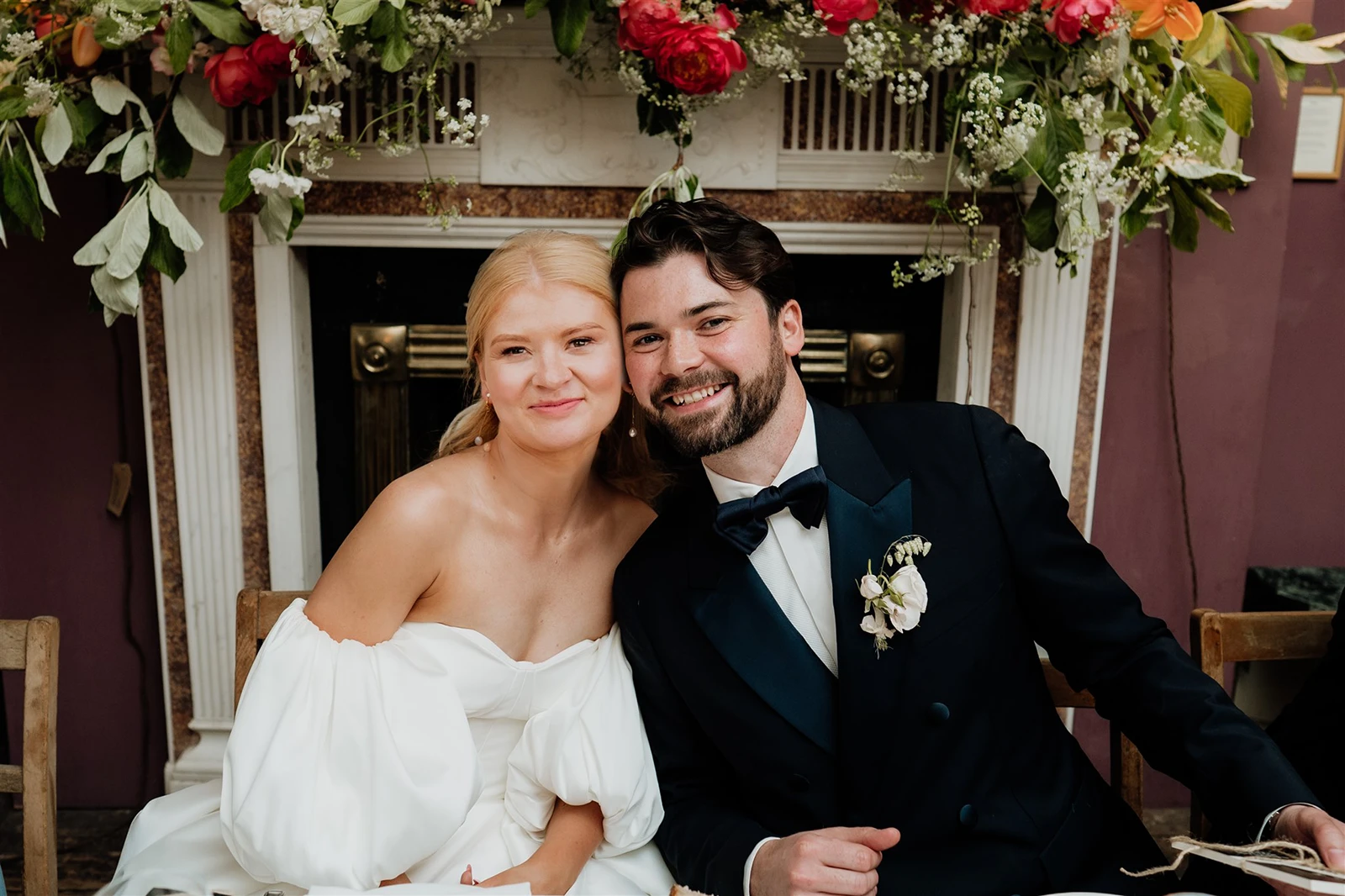 Bride and groom sitting together smiling during a wedding reception meal.