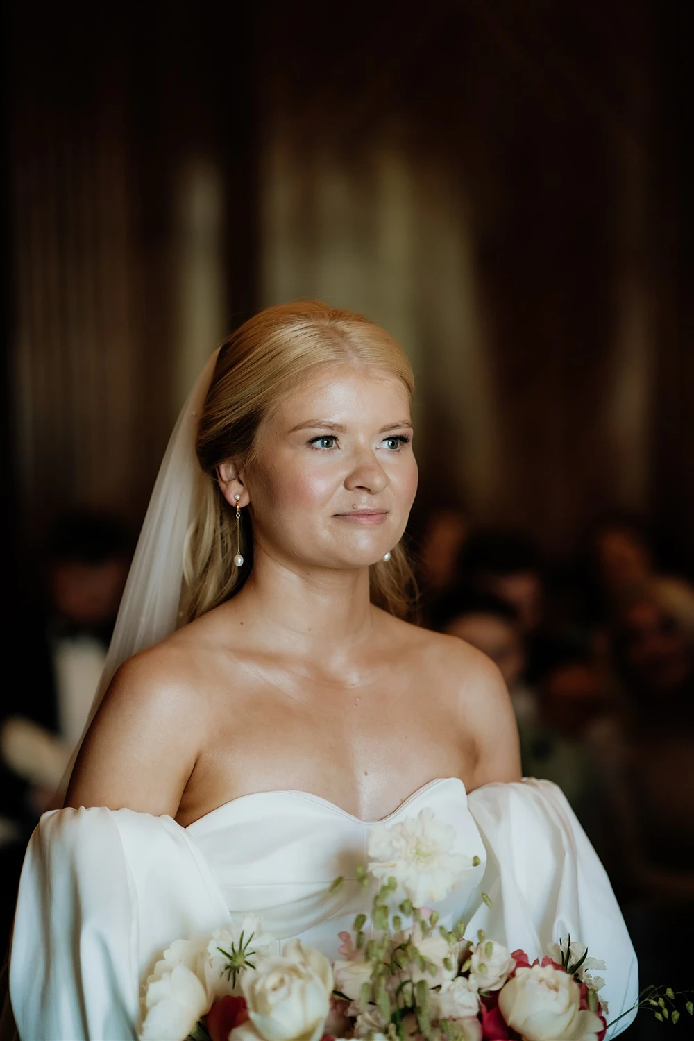 Close-up portrait of a bride wearing a veil and pearl drop earrings during a wedding ceremony at The Old Marylebone Town Hall