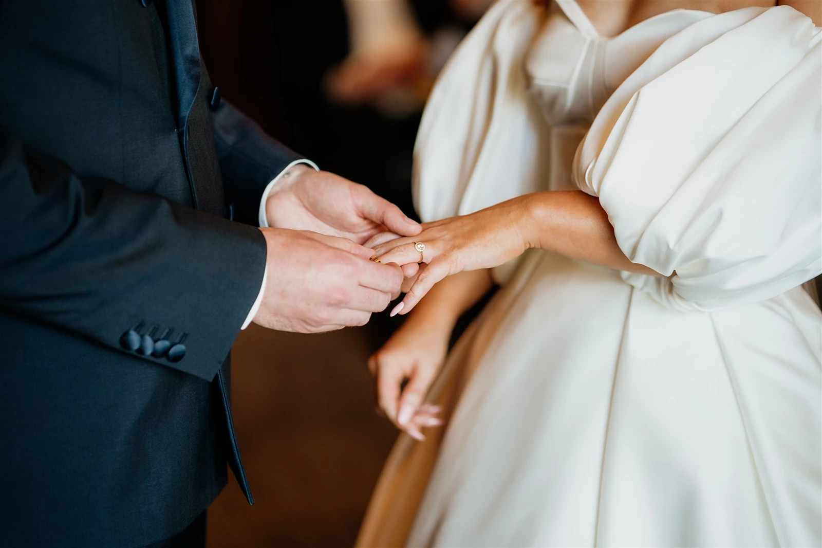 Groom placing a wedding ring on the bride’s finger during the ceremony.