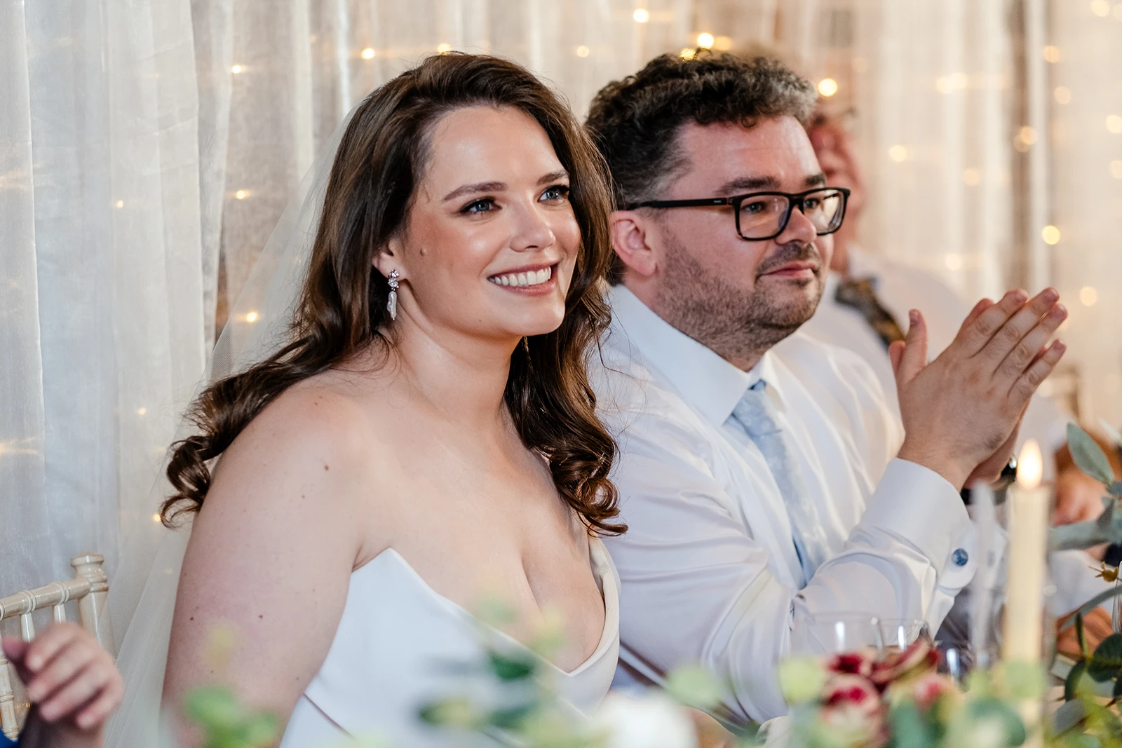 Bride and groom listening to wedding speeches at candlelit reception table